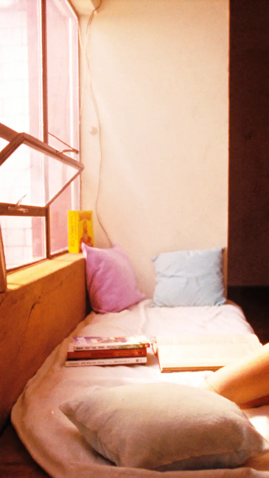 A sunlit reading nook with books and pillows